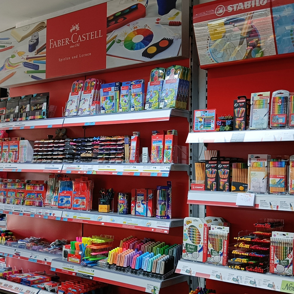 Die gut bestückte Schulwand des Malkasten mit Produkten von Faber Castell und Stabilo. Verschiedene Stifte, Marker und Schreibutensilien sind ordentlich angeordnet und bieten eine breite Auswahl an hochwertigen Schulmaterialien für Schüler aller Altersgruppen.